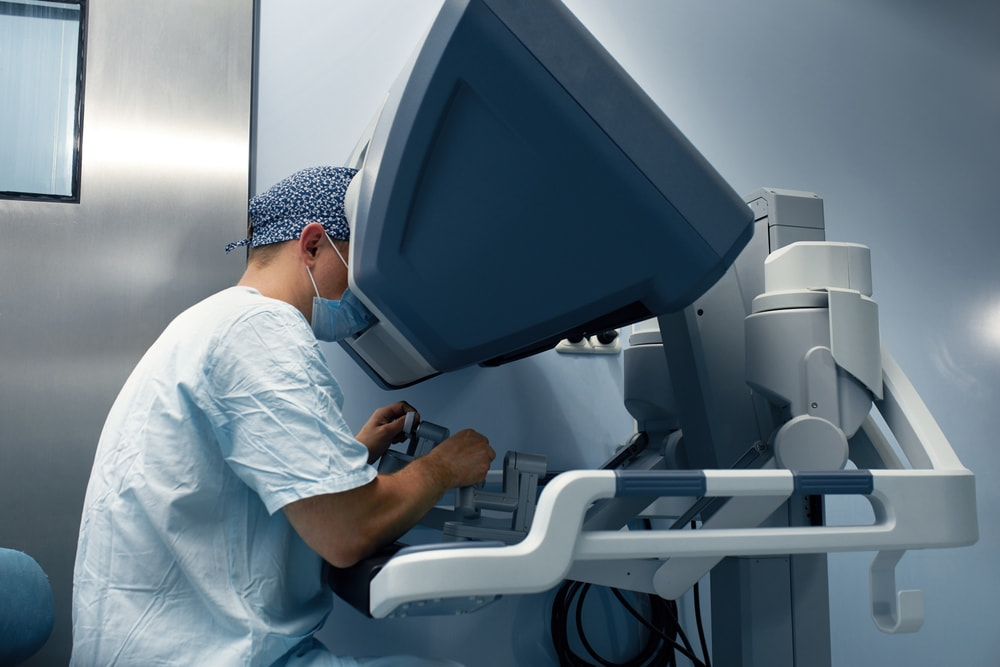 Médico utilizando computador para manuseio de aparelho robótico