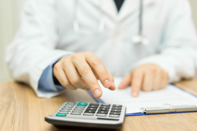 médico fazendo contas em cima de mesa de madeira