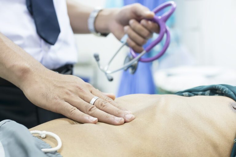 Médico examinando abdômen de paciente antes da herniorrafia inguinal