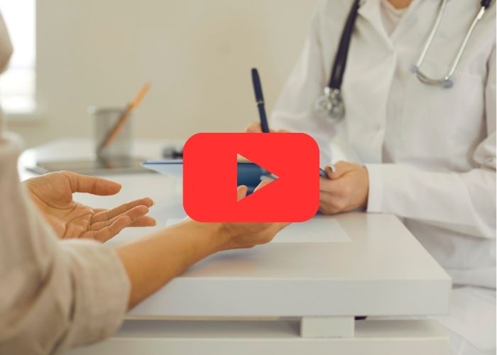 Pessoa em consulta médica com profissional da saúde; imagem com ícone do YouTube indicando conteúdo em vídeo sobre atendimento clínico.