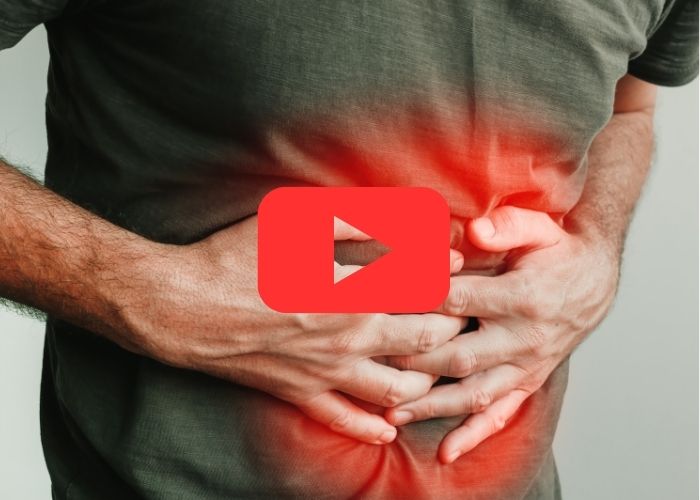 Homem com as mãos sobre o abdômen em sinal de dor intensa, com área vermelha destacando inflamação abdominal, indicando possível problema grave.