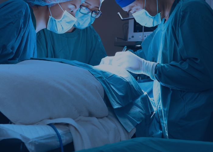 Equipe médica realiza cirurgia em centro cirúrgico, com foco no campo operatório iluminado e ambiente estéril.