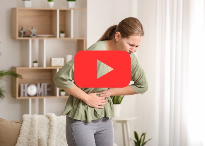 Mulher com jeans de cintura baixa mostrando o abdômen, enquanto profissional de luvas roxas examina região do umbigo com suspeita de hérnia umbilical.