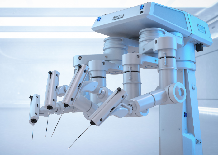 Braços robóticos cirúrgicos em ambiente hospitalar, com instrumentos finos na ponta, destacando tecnologia avançada para procedimentos médicos.