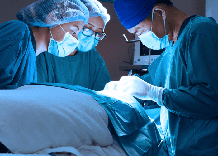 Equipe médica realizando cirurgia em centro cirúrgico, com foco nos profissionais concentrados no procedimento.