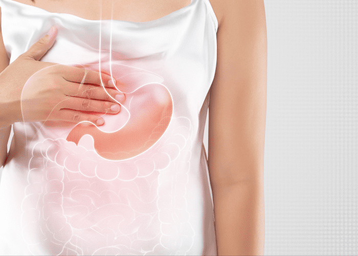 Pessoa segura a região do estômago com ilustração sobreposta do sistema digestivo, indicando dor ou refluxo.