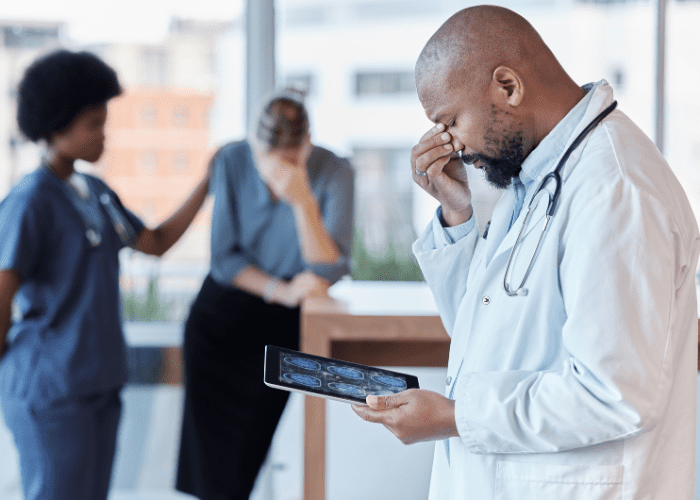 Médico com máscara e estetoscópio analisando prancheta, demonstrando preocupação ou dúvida em ambiente clínico.
