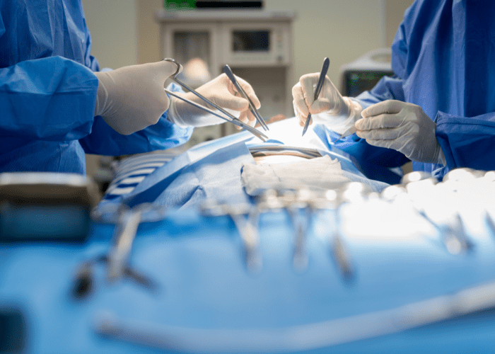 Equipe médica realizando procedimento cirúrgico com instrumentos em centro cirúrgico.